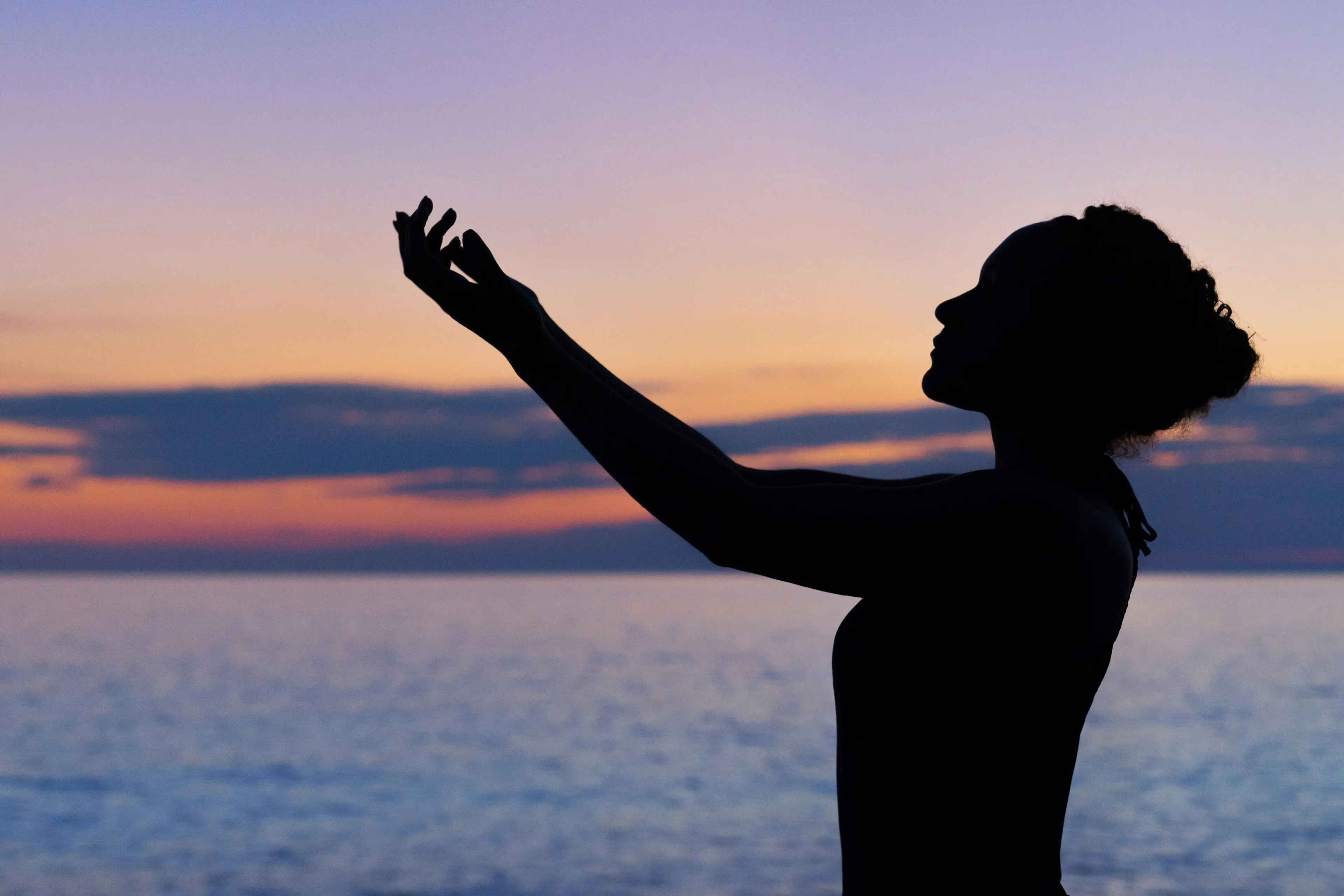 A silhouette of a lady posing in front of a beach sunset